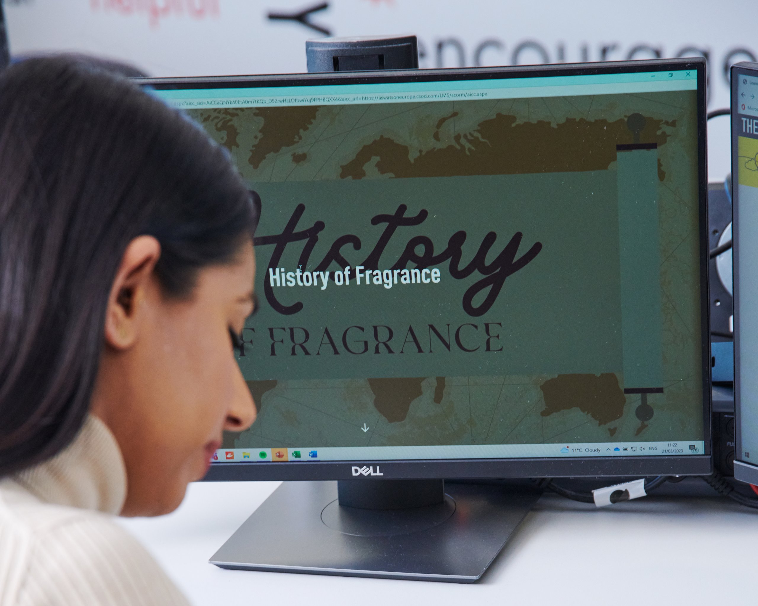 Person writing notes, studying "History of Fragrance" on a computer.