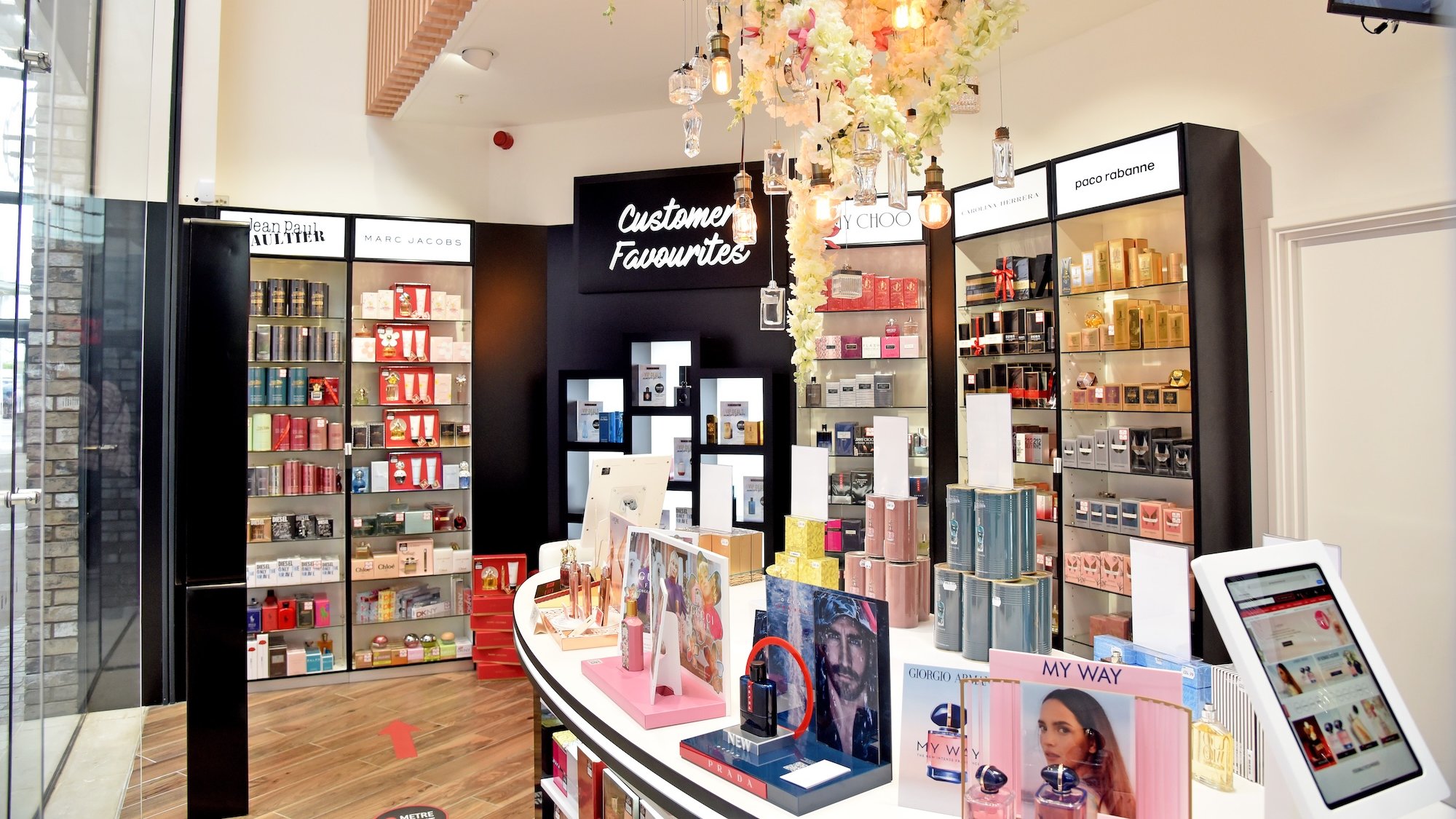 Perfume display shelves with floral decor and customer favorites sign.