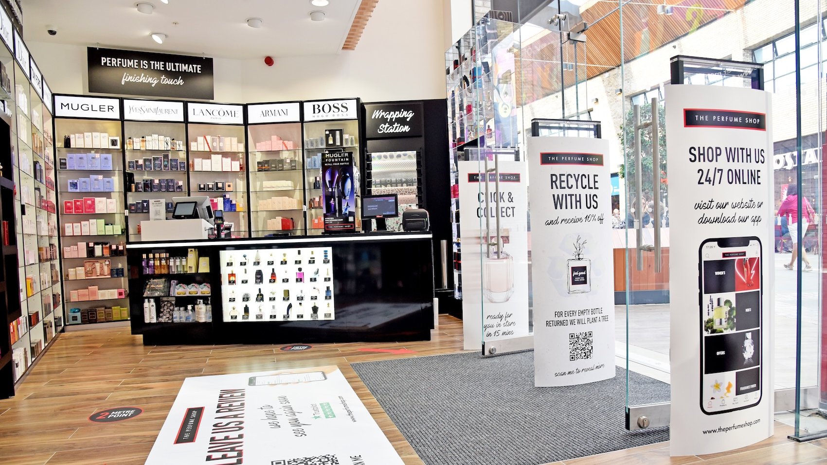 Interior of a perfume shop with perfume displays, signs, and entrances.