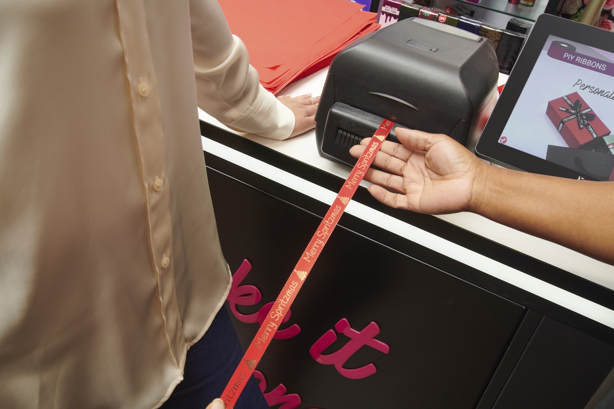 Person wrapping a gift with "Merry Spritzmas" ribbon.