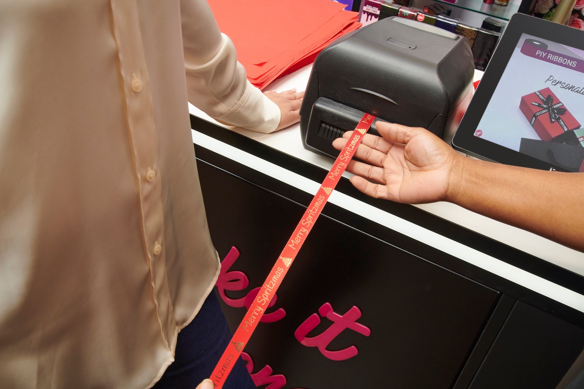 Person wrapping a gift with "Merry Spritzmas" ribbon.