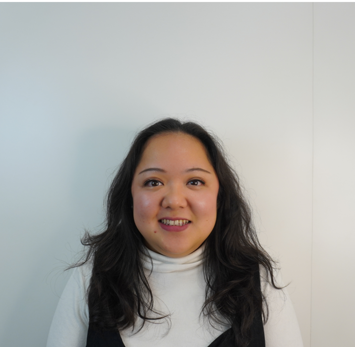 Woman with dark hair smiling at the camera, wearing a turtleneck.